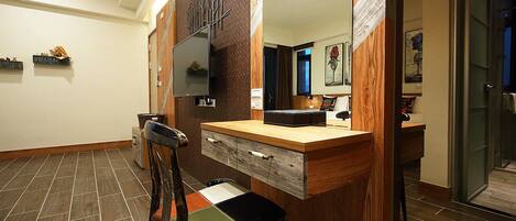 Un baño con tocador de madera, espejo y una silla.