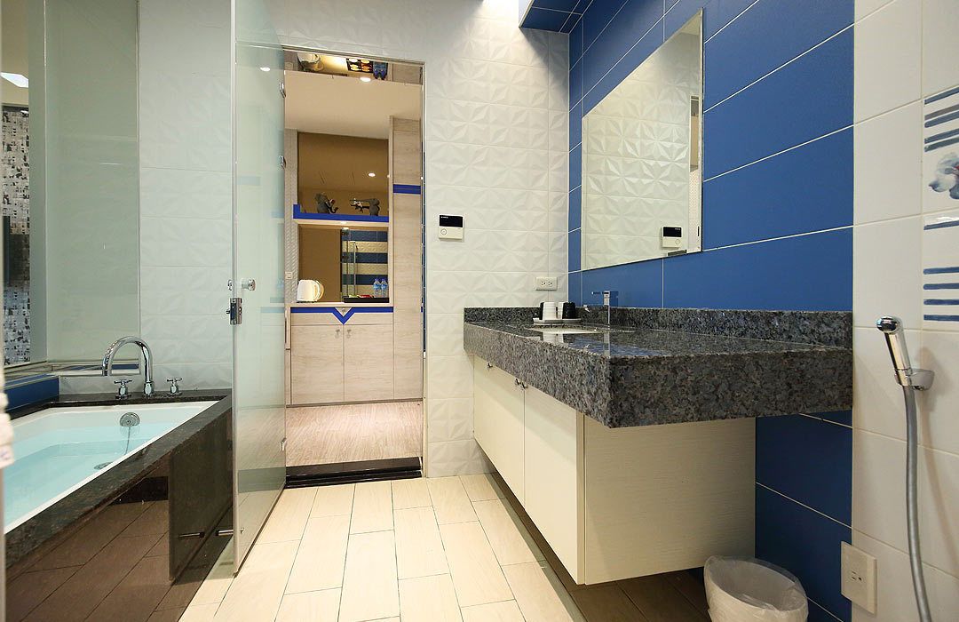 Een moderne badkamer met een douchecabine van glas, een wastafel met granieten blad en een grote spiegel.