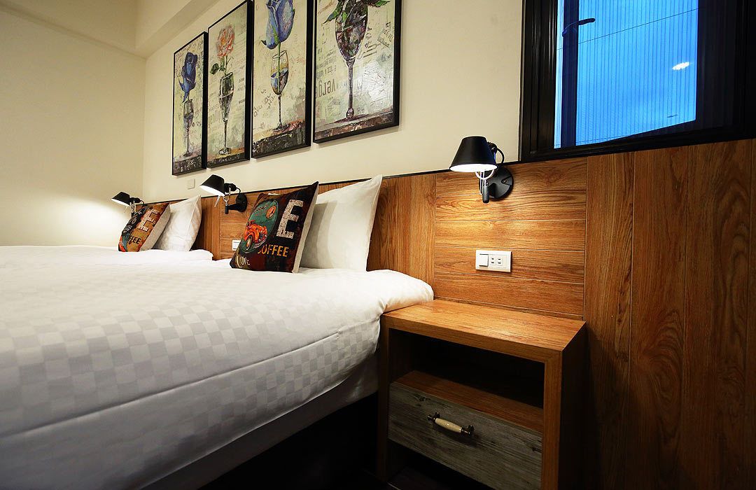 A bedroom with a wooden headboard, a bedside table with a lamp, and a window with a view of the sky.