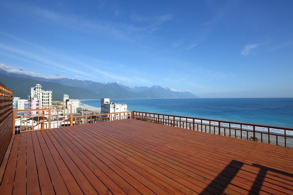 A wooden deck with a view of a beach and mountains.