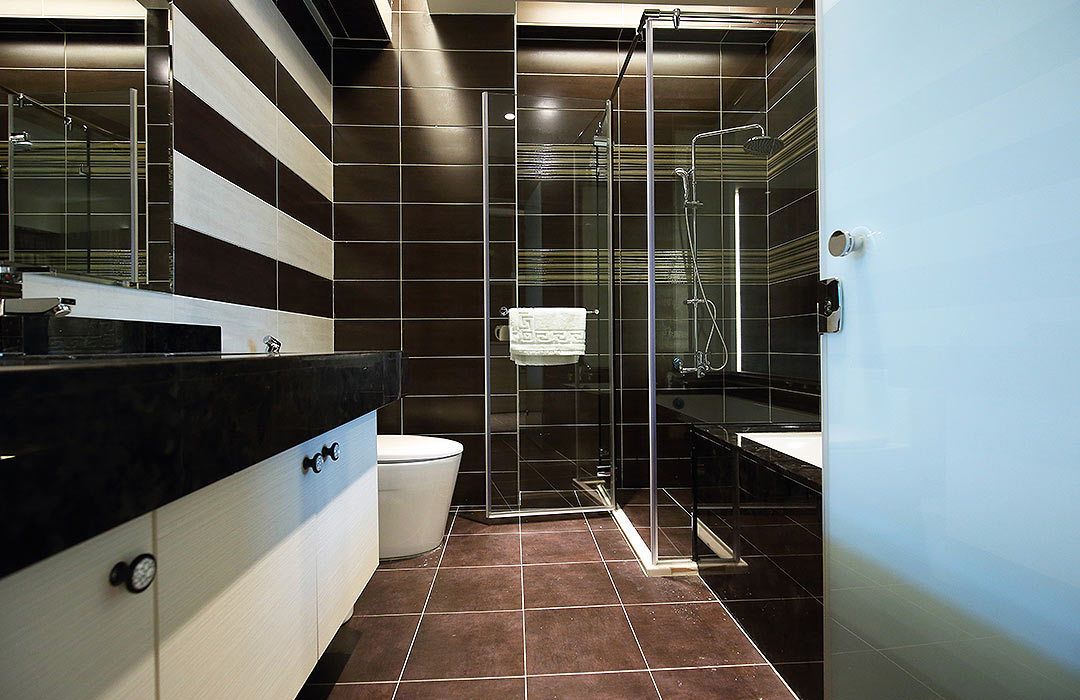 Un baño moderno con ducha de vidrio, pared con azulejos blancos y negros y encimera negra con lavabo.