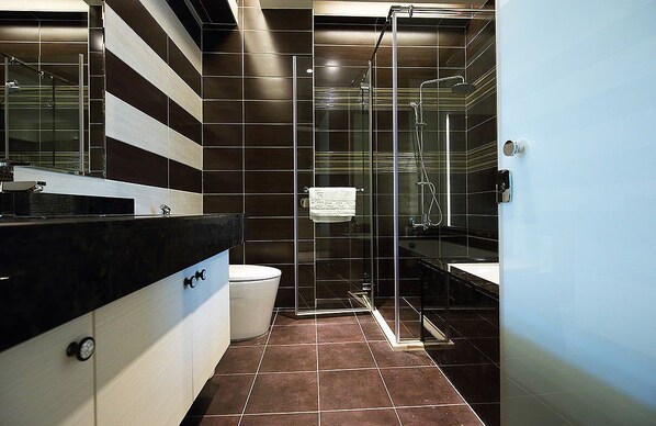 A modern bathroom with a glass-enclosed shower, a black and white tiled wall, and a black countertop with a sink.