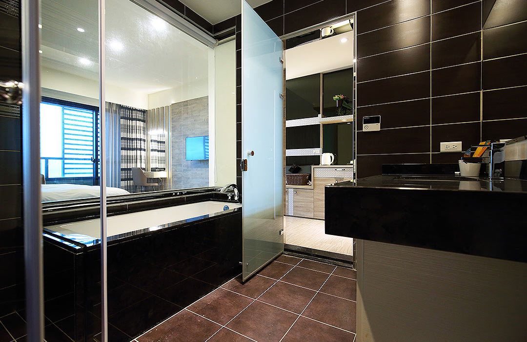 A modern bathroom with a glass shower enclosure, a black countertop, and a dark tiled wall.