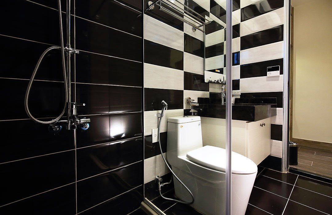 A modern bathroom with black and white checkered tiles, a glass shower enclosure, and a white toilet.