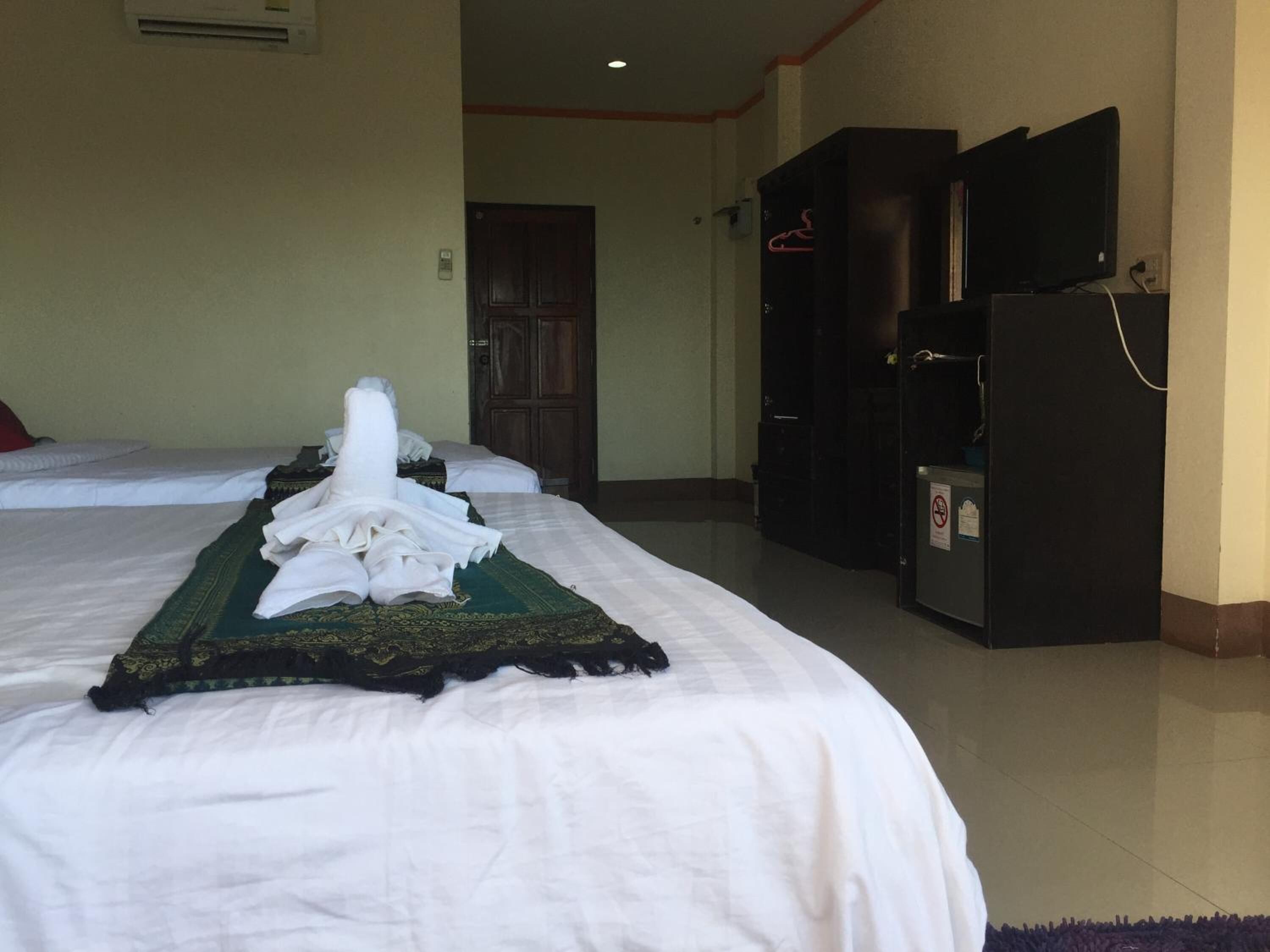 Ein Hotelzimmer mit zwei Betten, einem Fernseher und einem Kühlschrank.