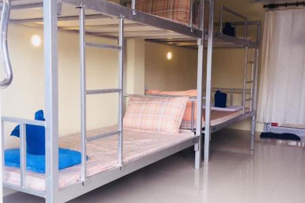 Ein Schlafraum mit Etagenbetten, einem weißen Boden, einem Deckenventilator und einer Klimaanlage.
