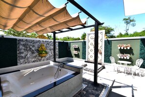 A spa area with a large bathtub, outdoor seating, and a decorative wall. - Relax Villa Hotel (Samut Prakan)