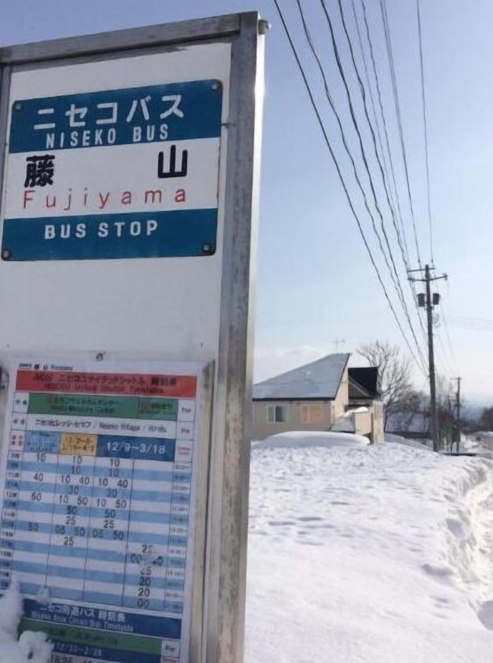A bus stop sign with "NISEKO BUS" and "Fujiyama" indicating the bus route.