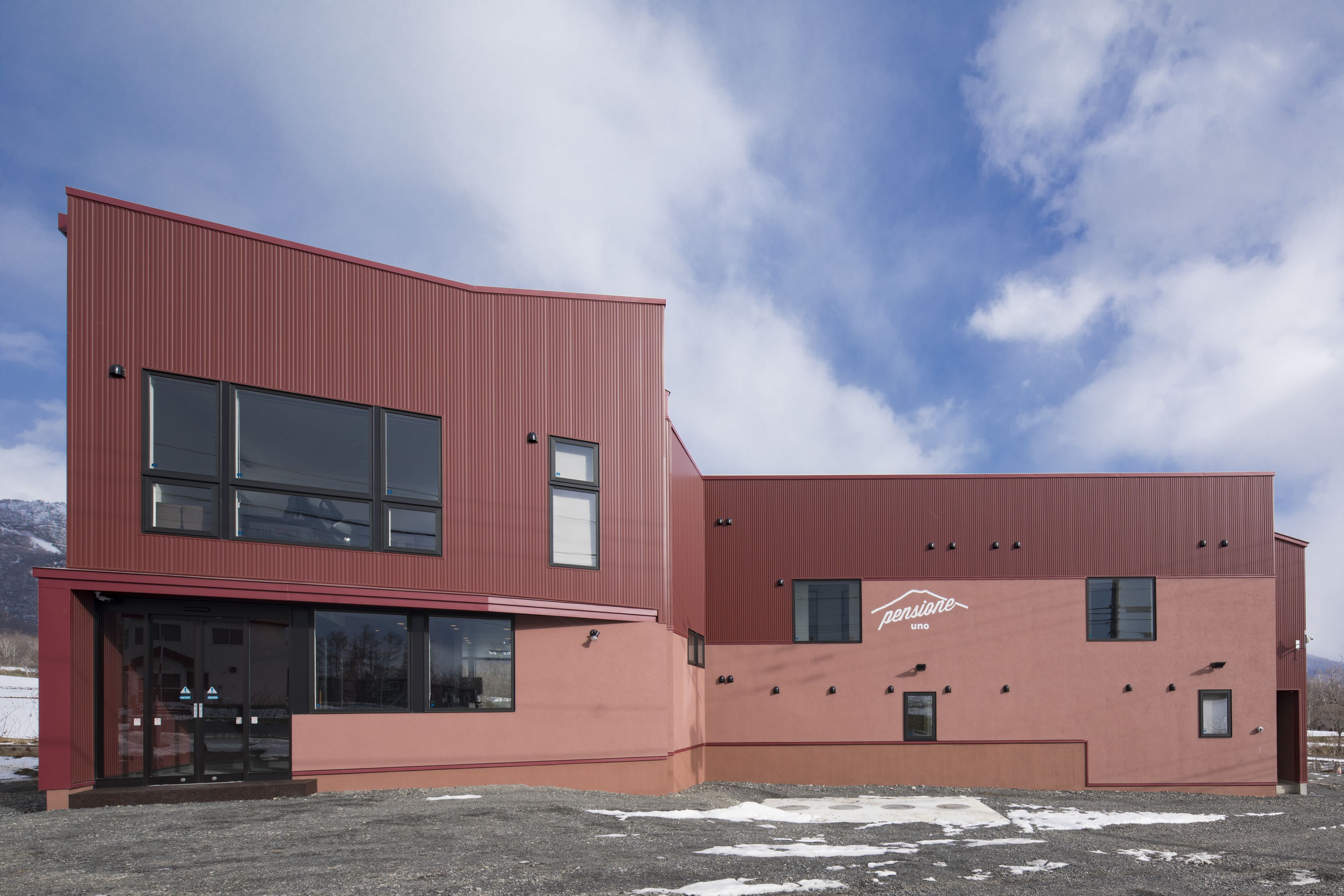 A modern building with a red facade, large windows, and a visible logo.