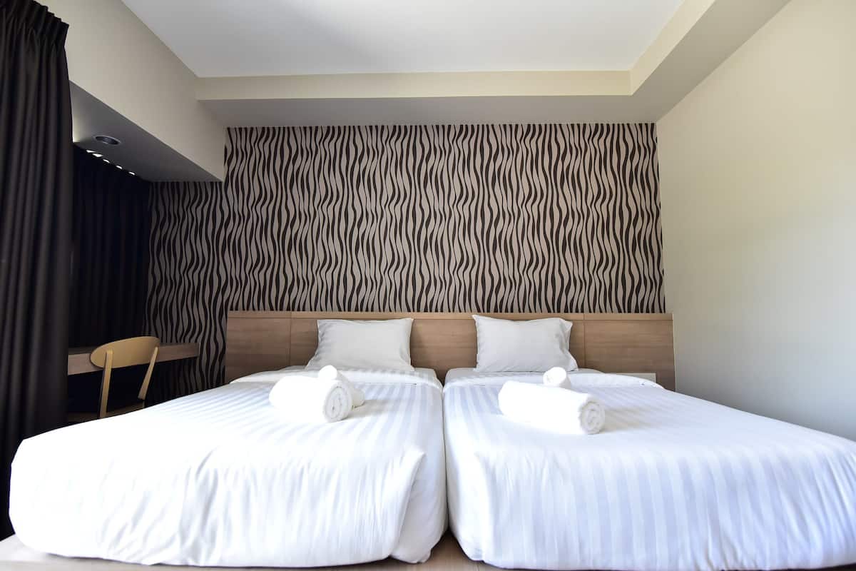 Une chambre d’hôtel avec deux lits, un bureau et un mur orné d’un motif zébré.