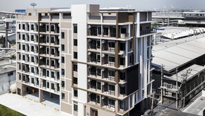 A multi-story building with a modern architectural design, featuring balconies and air conditioning units. - At S115 Residence (Samut Prakan)