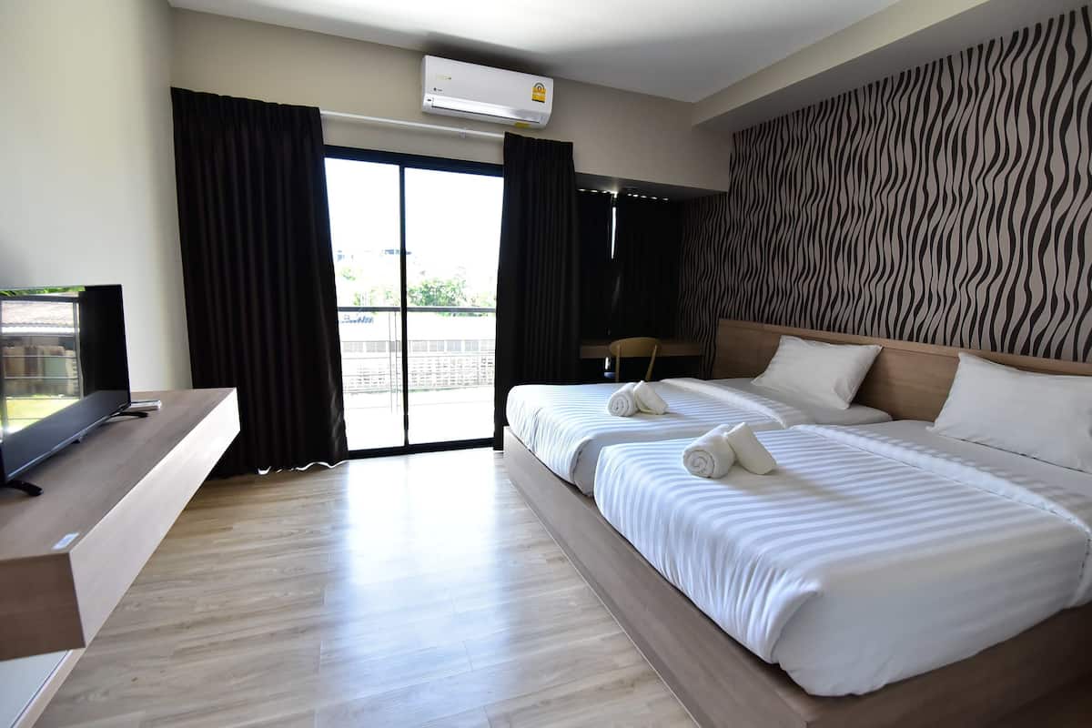 Une chambre d’hôtel avec un lit, une télévision, un bureau et une fenêtre avec des rideaux.