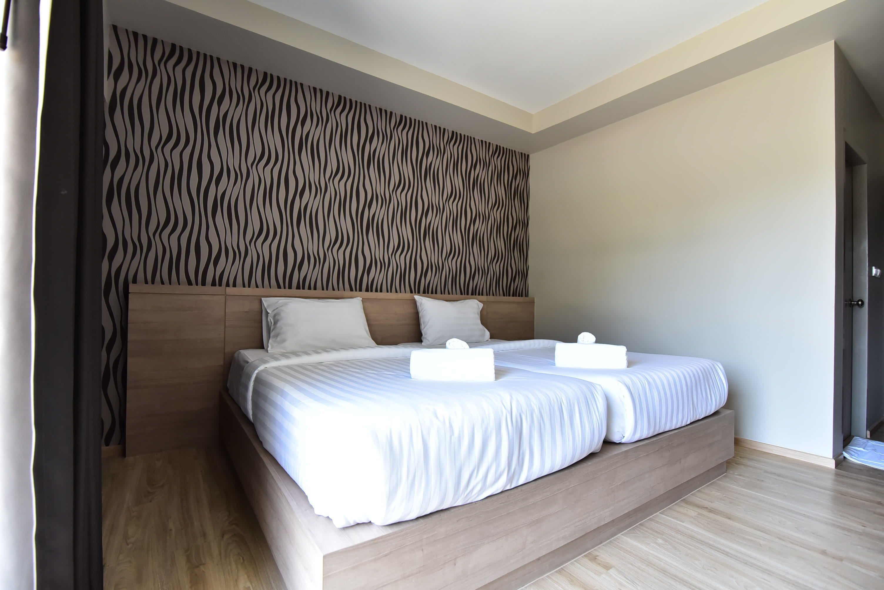 Un dormitorio moderno con una cama grande, cabecero de madera y pared con estampado.