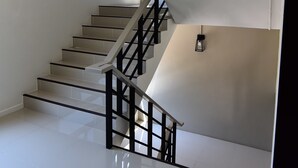 A modern staircase with a black railing and a light fixture on the landing. - At S115 Residence (Samut Prakan)