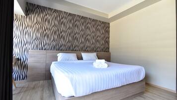 Una habitación de hotel moderna con una cama grande, cabecera de madera y pared con un diseño ondulado.