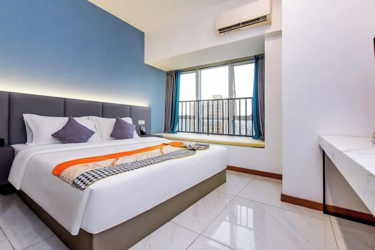 Une chambre d’hôtel moderne avec un grand lit, une fenêtre donnant sur un beau paysage et un petit espace bureau.