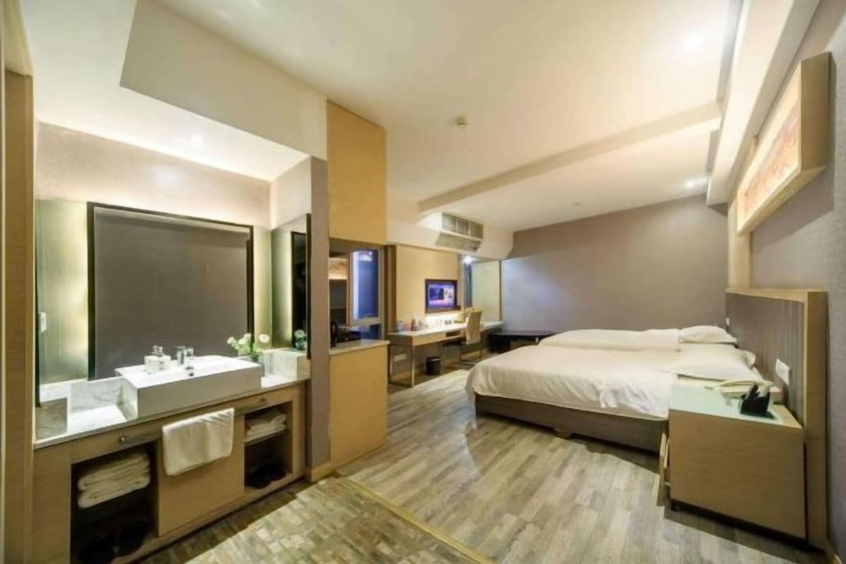 Une chambre d’hôtel moderne équipée d’un grand lit, d’un bureau, d’une coiffeuse avec miroir et d’une télévision.