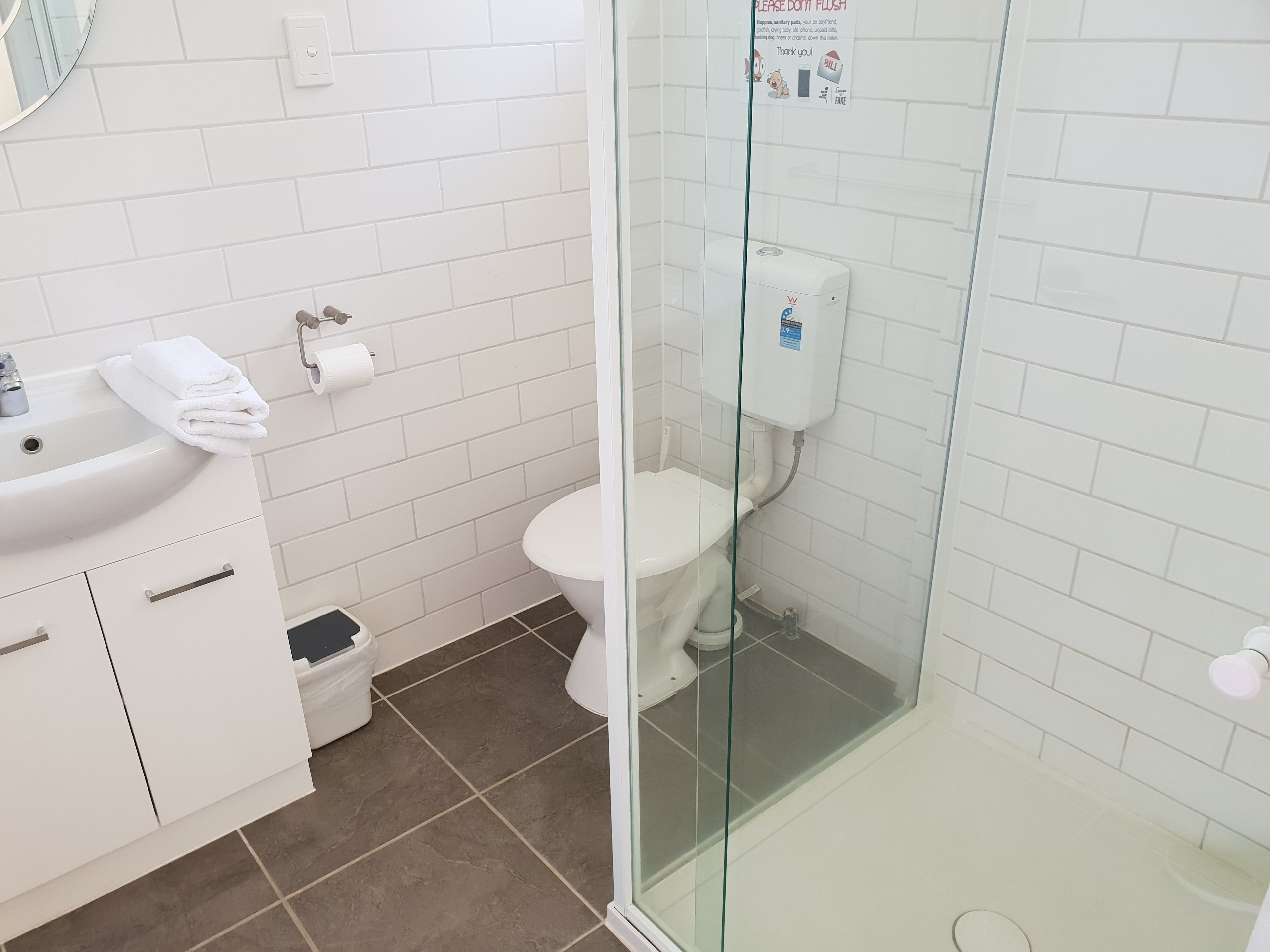 Une salle de bain avec un lavabo blanc, des toilettes et un espace douche.