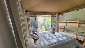 Una habitación con una cama, literas y una puerta corrediza de vidrio que da a un espacio exterior.