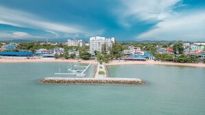 Un paysage urbain côtier avec un grand hôtel blanc qui se distingue, une plage de sable et une marina paisible.