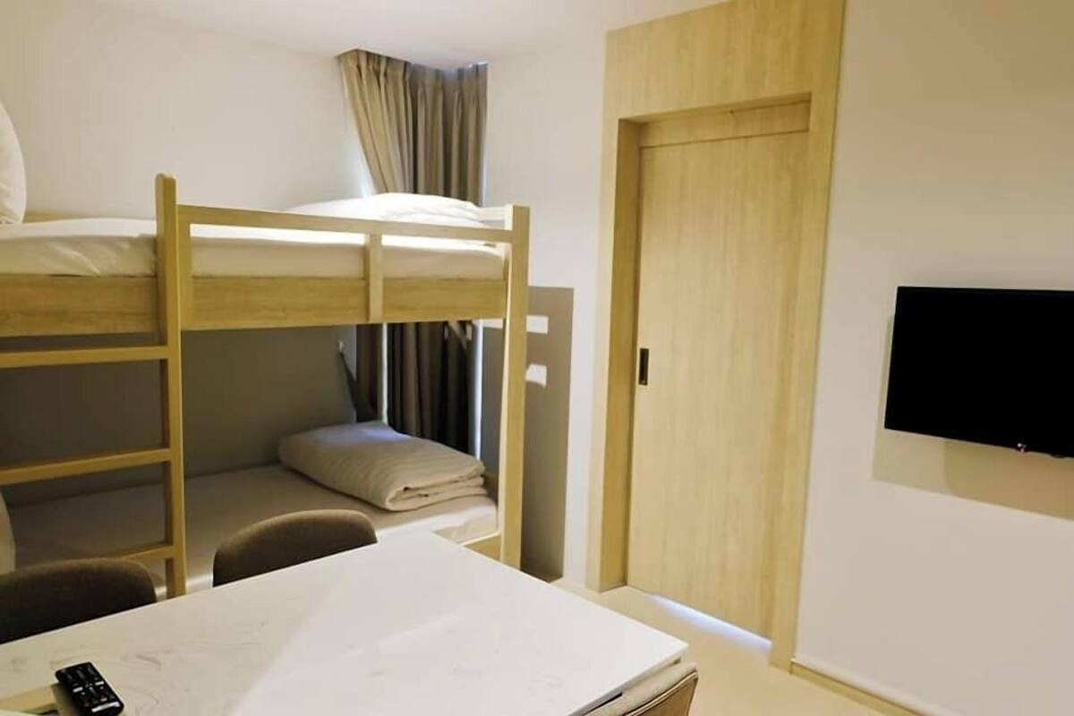 Habitación con literas, escritorio, silla, televisor y armario.