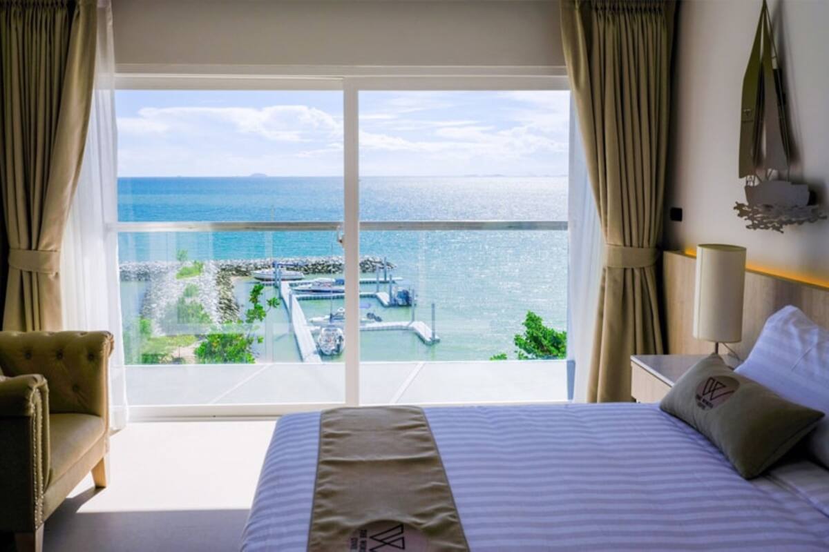 Habitación de hotel con una cama grande, vistas al mar y un balcón con vista a un puerto deportivo.