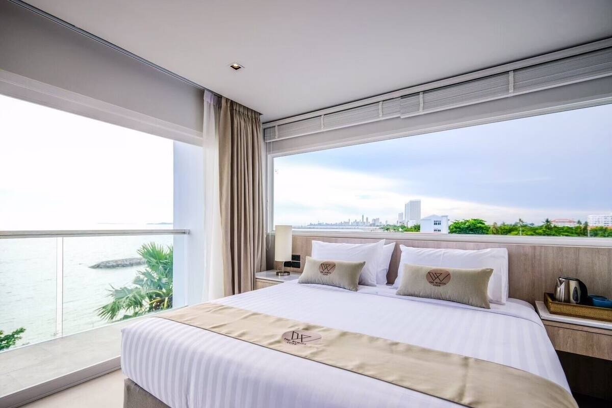 Habitación de hotel moderna con una cama grande, una mesita de noche y vistas a la silueta urbana.