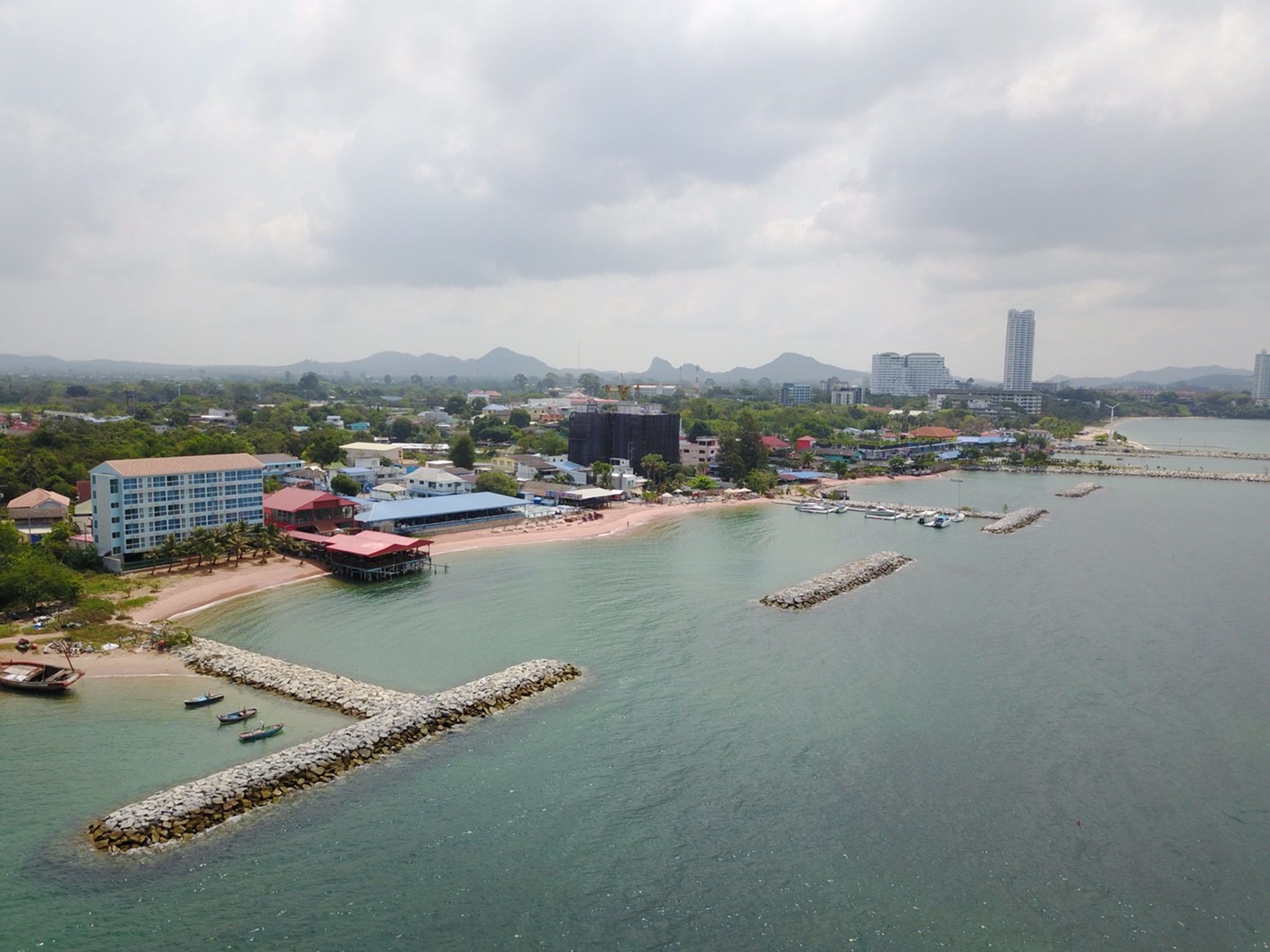 Un pueblo costero con playa, barcos y edificios.