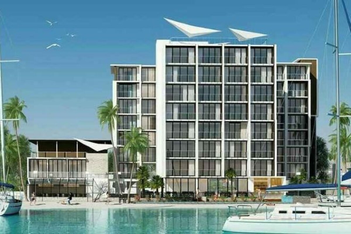 Ein modernes Hotel mit einer rechteckigen Fassade, mehreren Balkonen und einem Poolbereich.