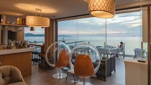 Un intérieur moderne avec un espace bar, des chaises en verre transparent et une vue sur la mer.