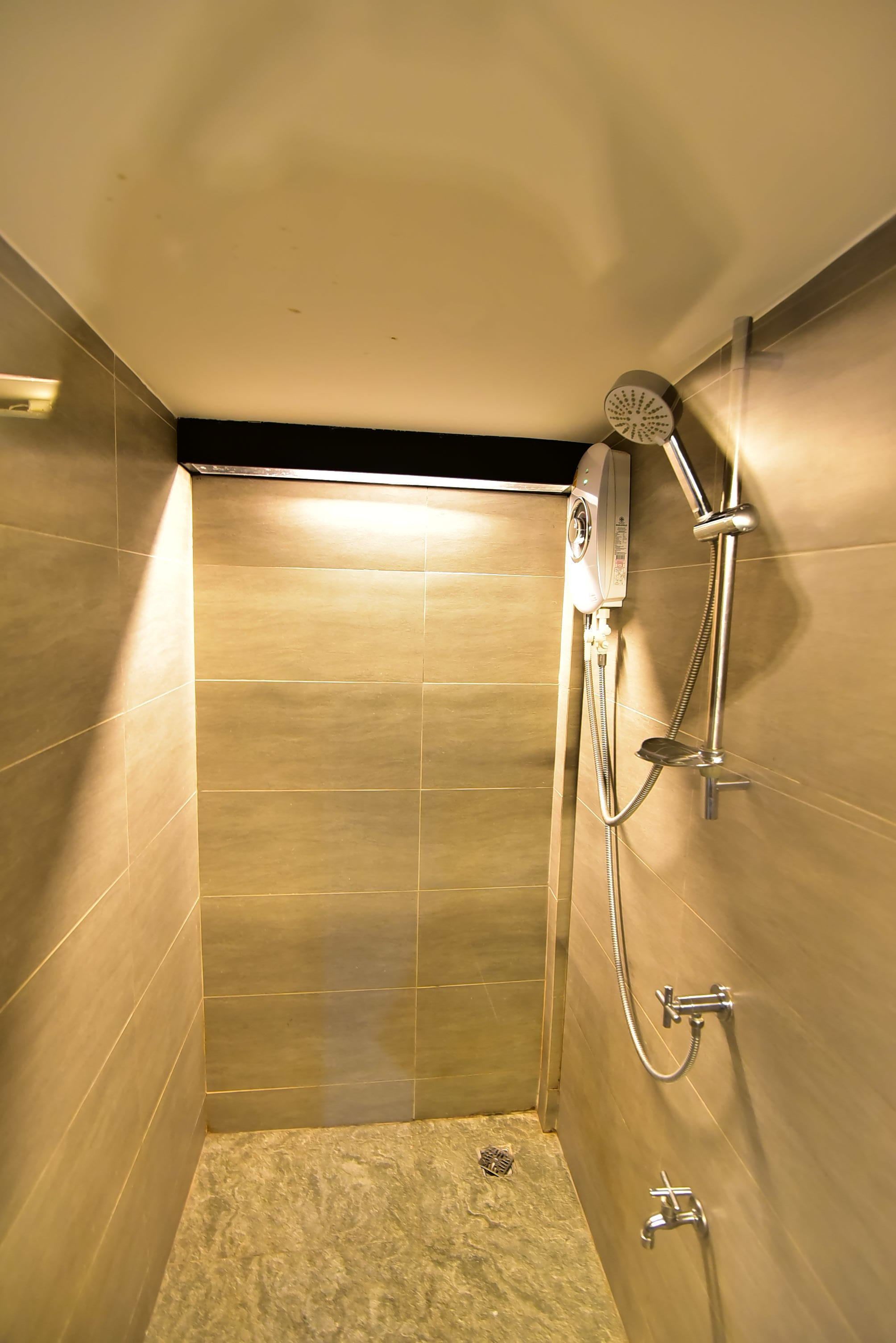 A small, modern shower stall with a handheld showerhead and a handheld shower attachment.