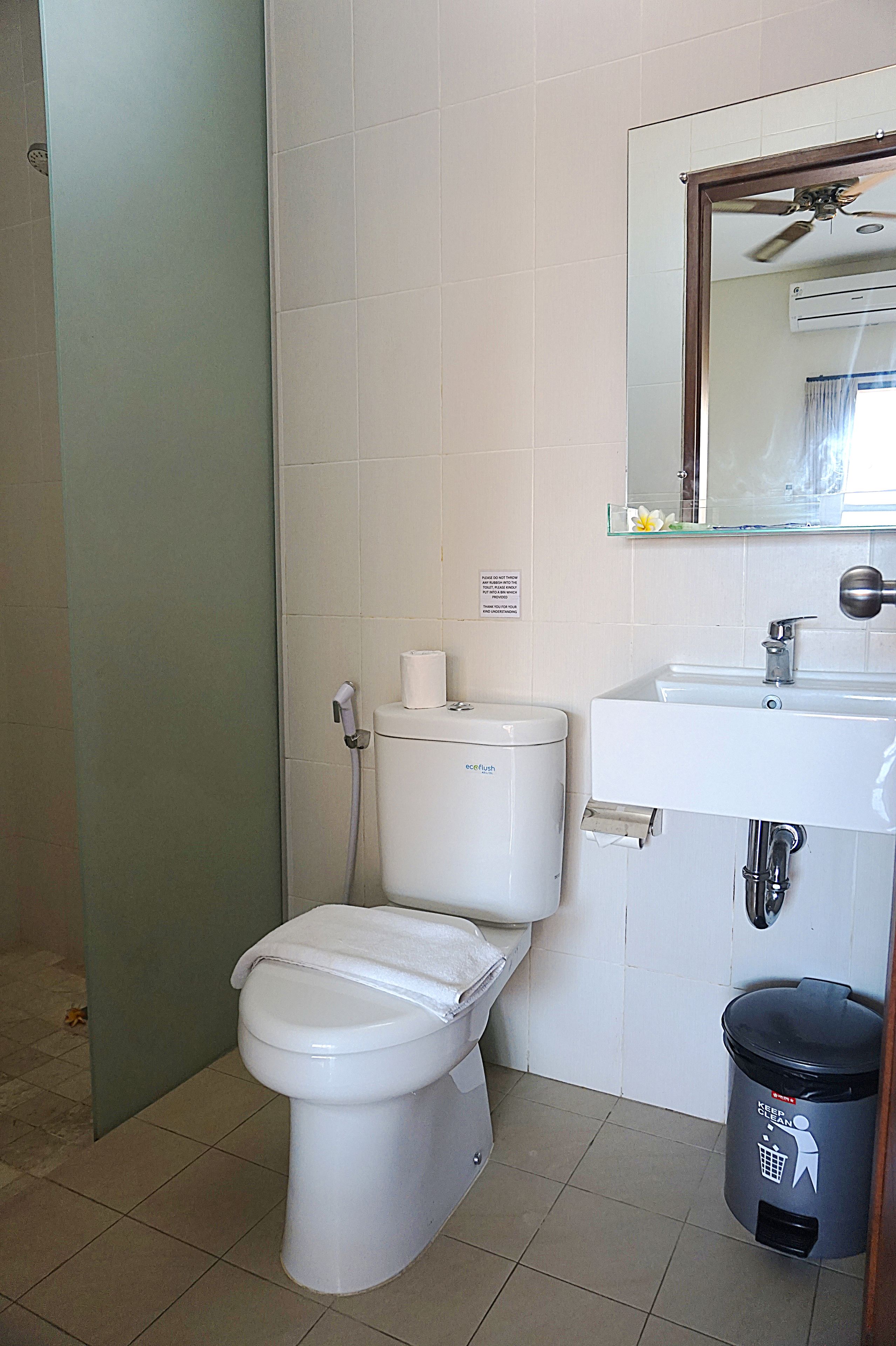 A small bathroom with a toilet, sink, and mirror.