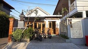 A residential building with a tiled roof, a small shrine, and two motorcycles parked in front. - Sweet Corner Guest House (Denpasar)