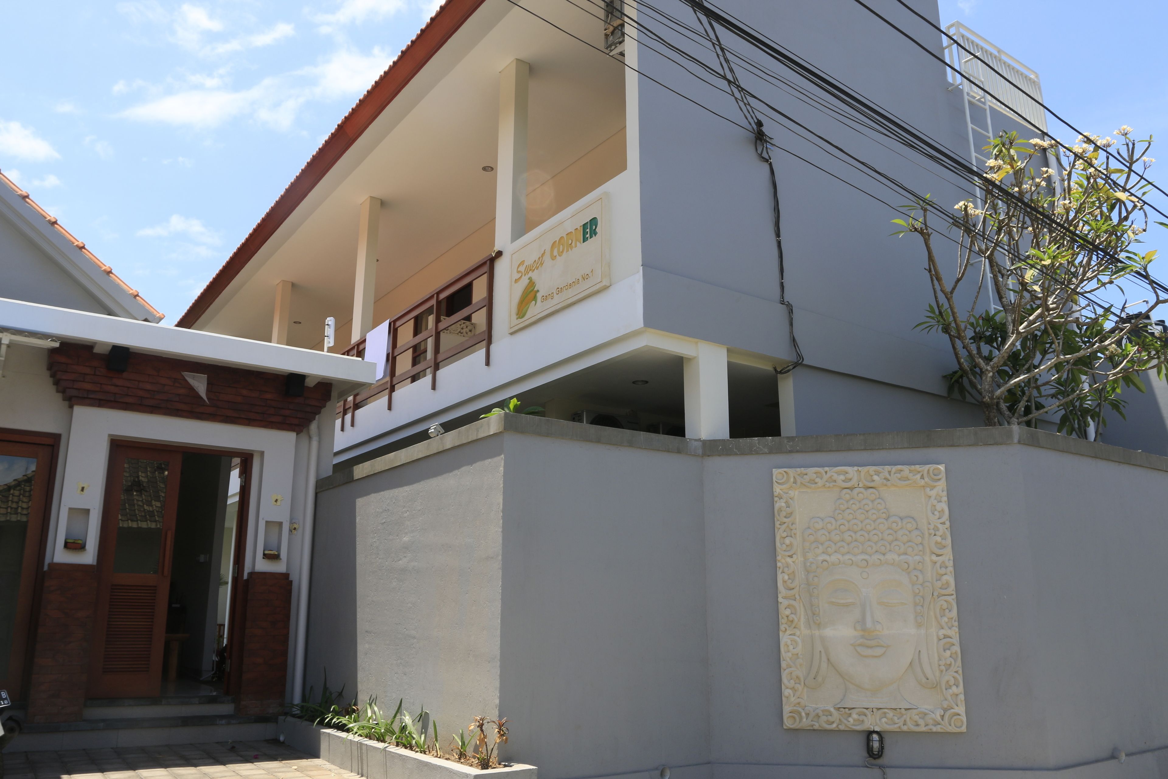 A building with a sign reading "Sweet Corner" and a Buddha statue on the wall.