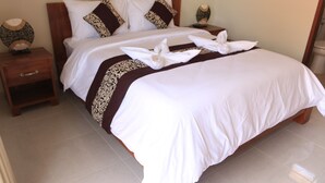 A double bed with white and brown bedding, two nightstands, and a wooden headboard. - Sweet Corner Guest House (Denpasar)