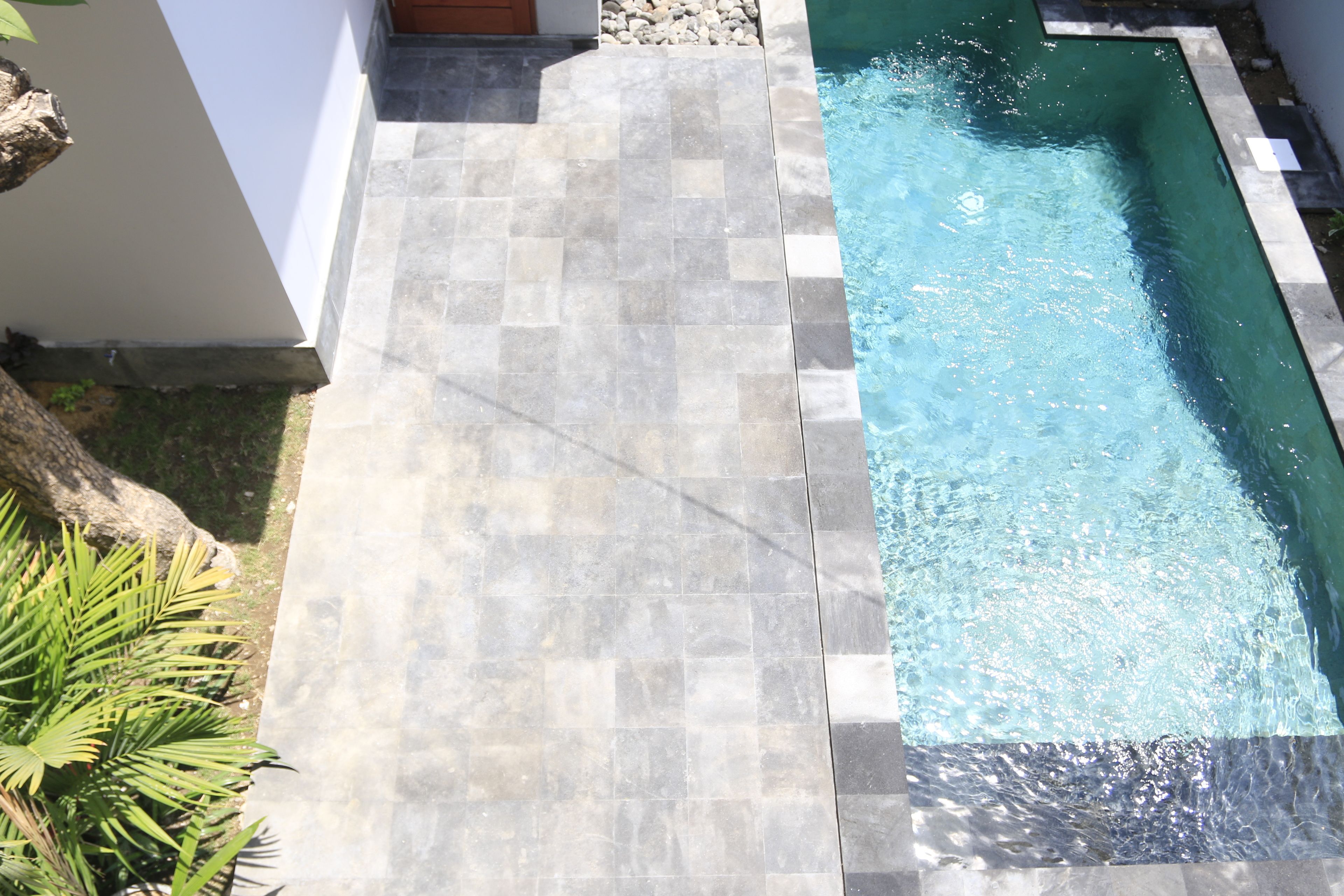 Una piscina rectangular con agua cristalina, rodeada por una solería azulejada.
