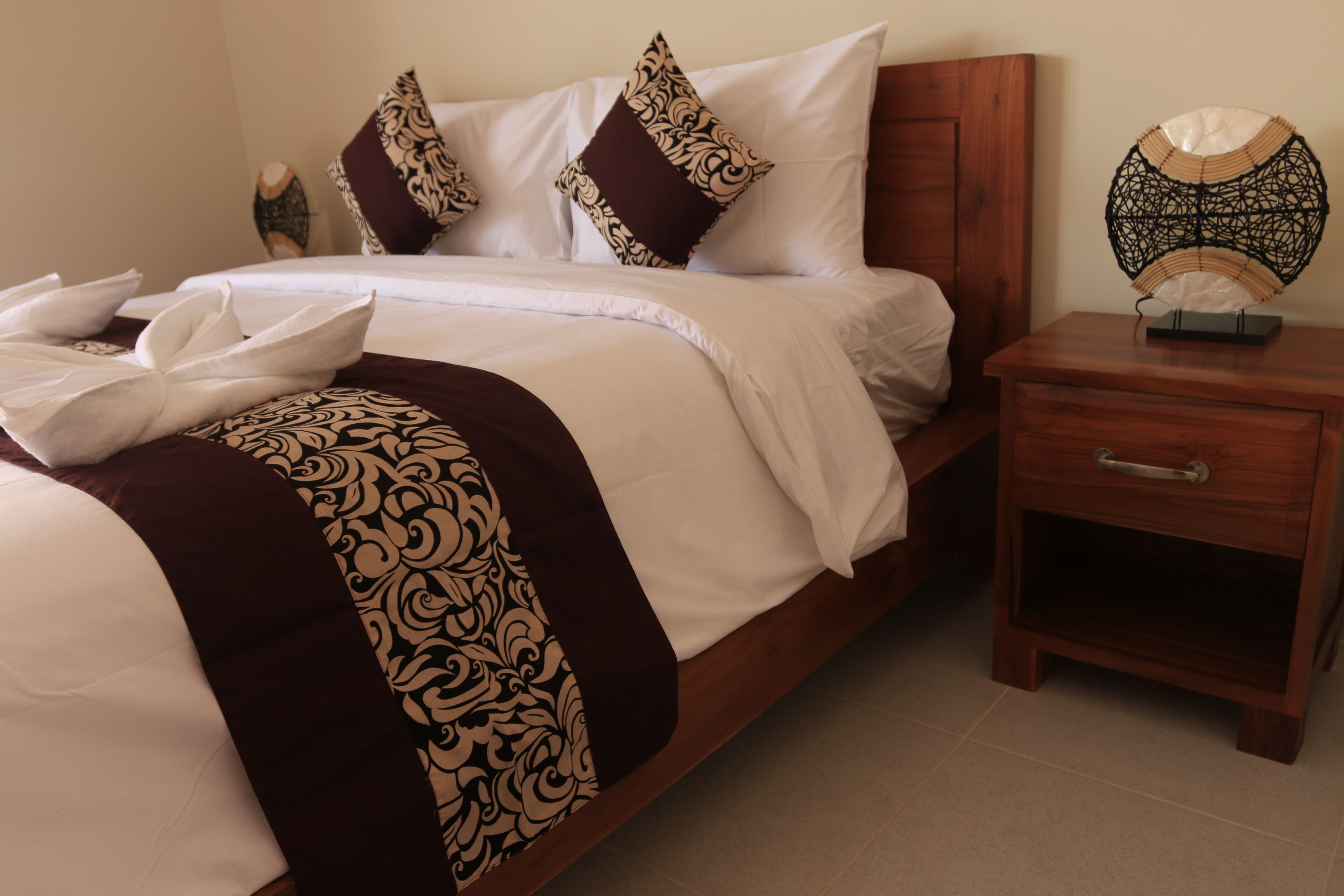 Una cama bien hecha con almohadas estampadas y un cabecero decorativo.