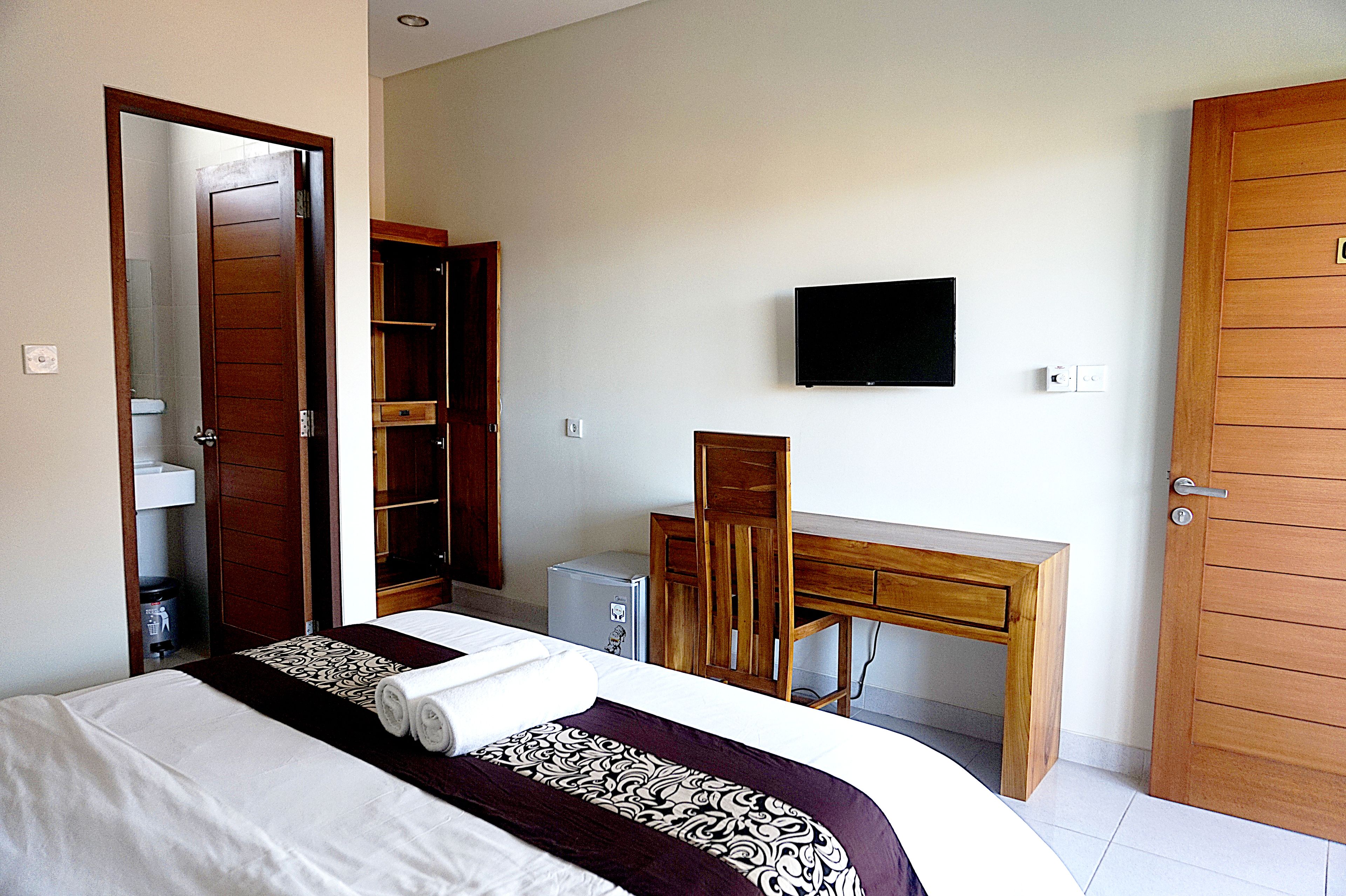 Una habitación de hotel con cama, escritorio, televisor y armario.