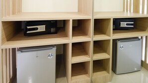 A modern storage unit with multiple compartments, including a small refrigerator and a cabinet with a hanging rack. - Hop Inn Hotel Alabang Manila (Muntinlupa)