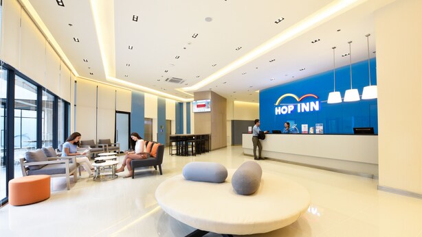 A modern hotel lobby with a reception desk, seating area, and a large window. - Hop Inn Hotel Alabang Manila (Muntinlupa)