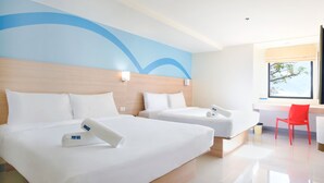 A hotel room with two beds, a wooden headboard, a red chair, and a window with a view of trees. - Hop Inn Hotel Alabang Manila (Muntinlupa)