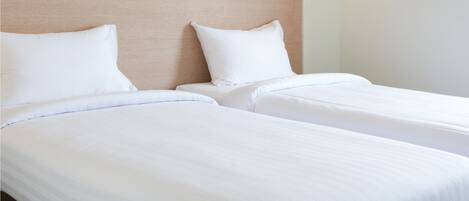 A hotel room with two beds, a blue suitcase, and a wall with a blue abstract design.