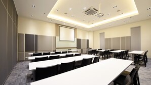 A conference room with multiple tables and chairs, a projector screen, and a large screen on the wall. - Hop Inn Hotel Alabang Manila (Muntinlupa)