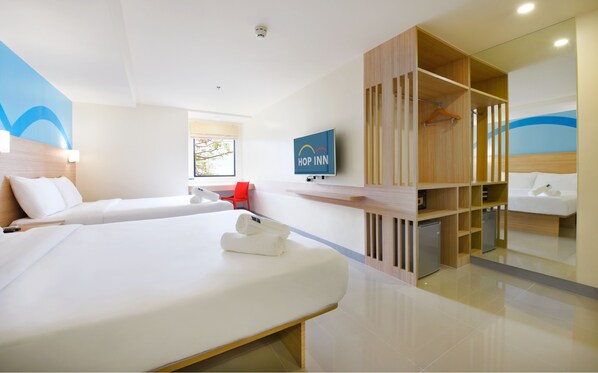 Quarto de hotel moderno com uma cama grande, uma televisão, um guarda-roupa de madeira e uma cadeira vermelha.