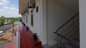 Edifici amb un balcó pavimentat de color vermell, una escala i diverses unitats de climatització a la façana.