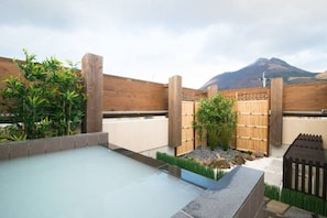 Área de piscina en la azotea con valla de madera, un pequeño jardín y vistas a la montaña.