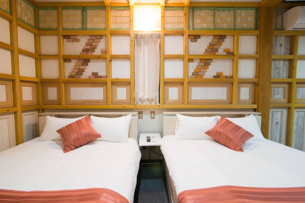 A room with two beds, a small table, and a curtain.