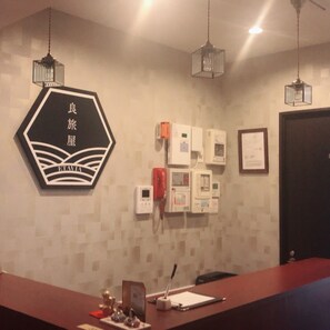 A reception desk with a sign reading "ETAVIA" and a wall-mounted fire alarm. - Etavia Yufuin ekimae (Yufu)