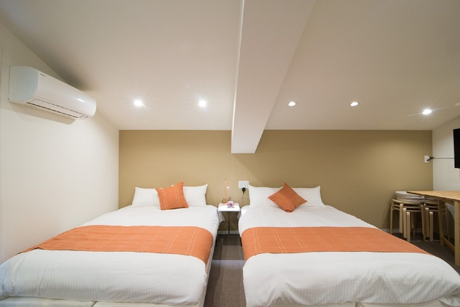 A hotel room with two beds, a small table, and a desk.
