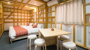 A room with a bed, a table, and two stools. - Etavia Yufuin ekimae (Yufu)